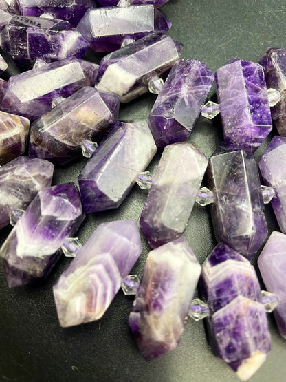 AAA Natural Amethyst stone bead. 12x26-12x34mm graduated barrel shape. Gorgeous natural purple color with white lines. Full strand 15.5”