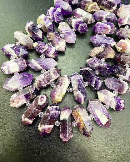 AAA Natural Amethyst stone bead. 12x26-12x34mm graduated barrel shape. Gorgeous natural purple color with white lines. Full strand 15.5”